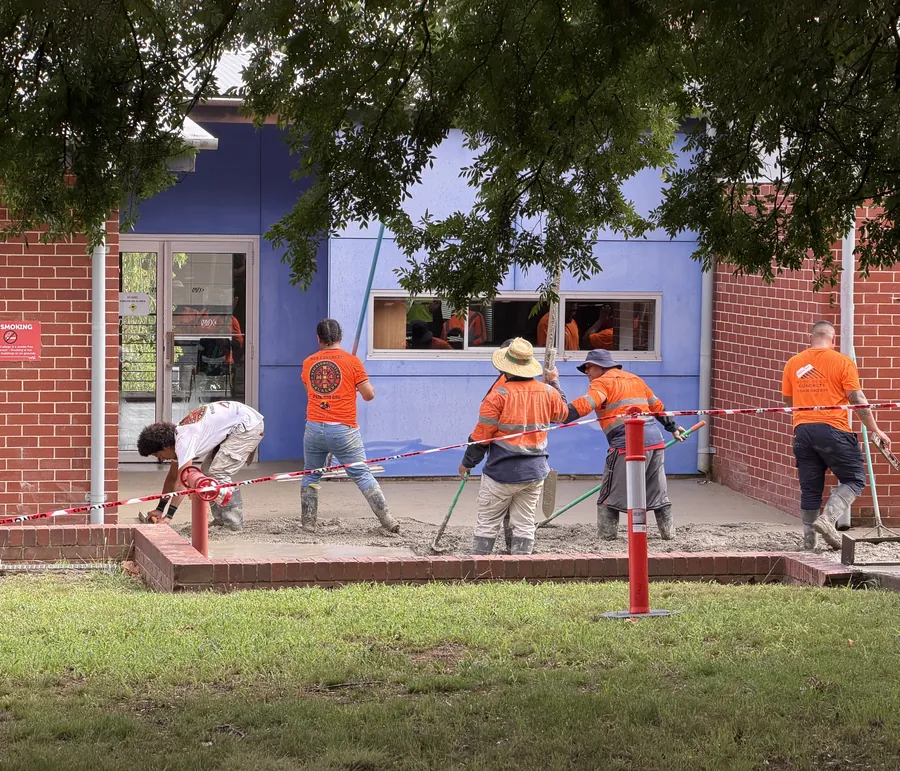 Baywa crew pouring a concrete slab beside a school building